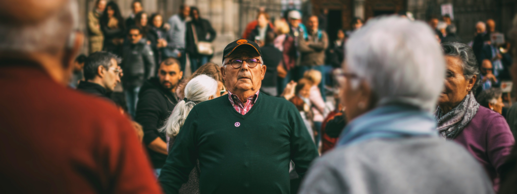 Older adults gathered in a public square representing aging communities.